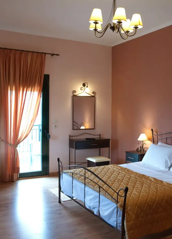 view of a hotel room with a double bed and a balcony door at the background