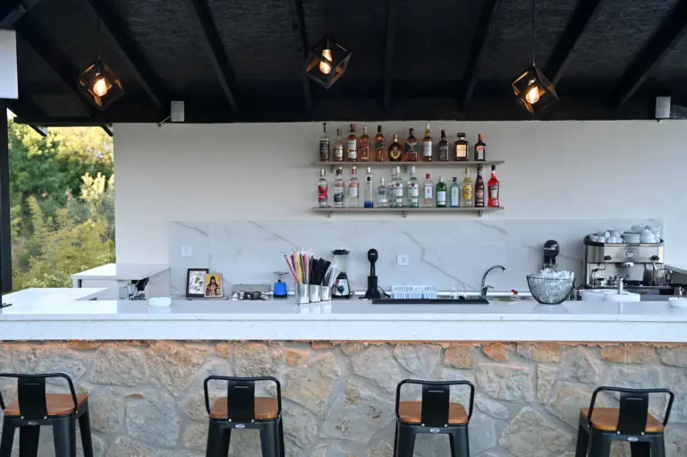 close up view of the hotel stone bar with stools and a wooden roof