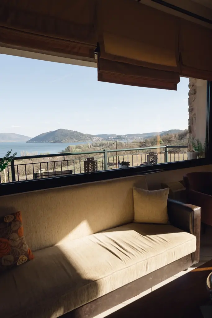 photo through a large window of the lake with rays of sunlight striking down on the furniture