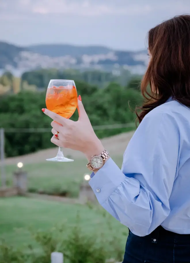 realistic photo of a woman holding a refreshing drink in her hand with the nature greenery as a background